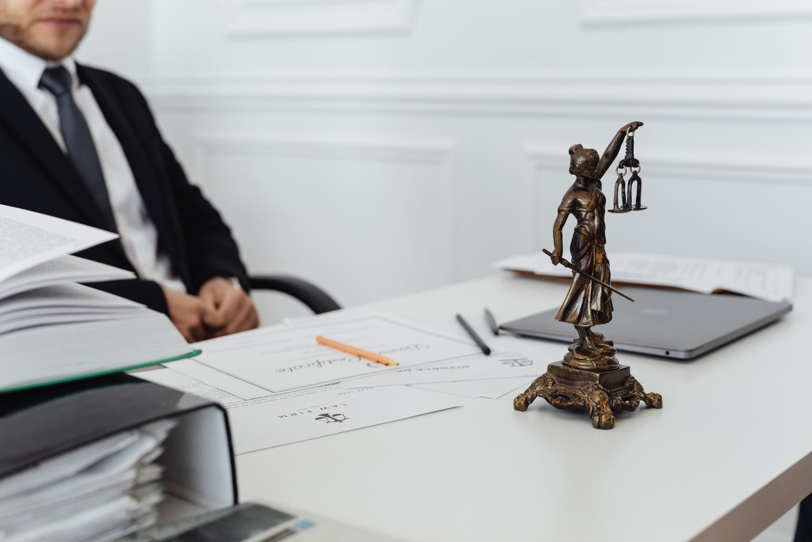 Despacho de abogados con una estatua de la justicia frente a estanterías de jurisprudencia