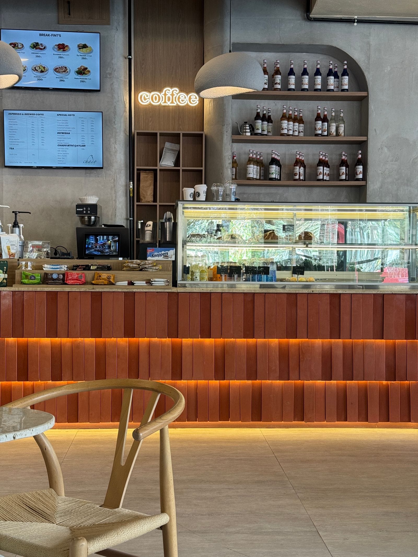 Interior cálido de Cafè Aurora con barra de mármol, banquetas de madera y luz de tarde