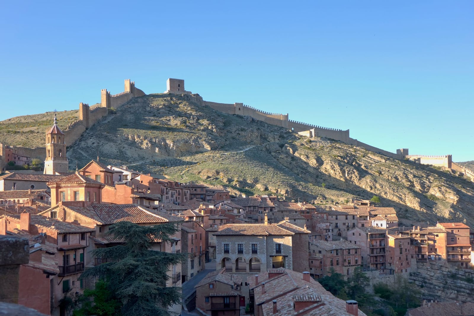 Pueblo de piedra rodeno rojiza sobre una sierra de interior al atardecer, junto a Mas de les Espigues