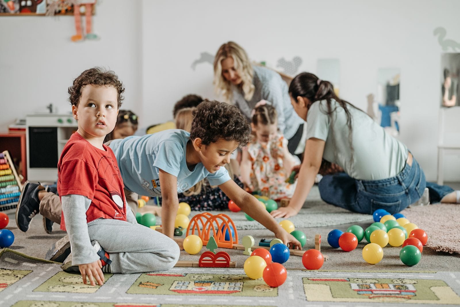 Varios niños y niñas juegan sentados en el suelo del aula, manipulando materiales